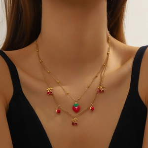 Double-layered gold necklace featuring cute red strawberry and cherry charms on a model