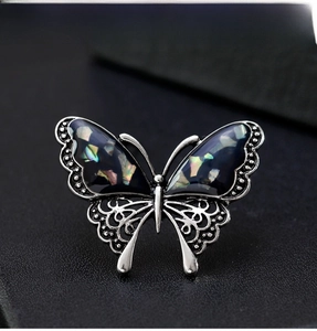 Macro shot of silver butterfly brooch featuring iridescent shell wings and intricate filigree