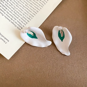 Detailed view of white calla lily earrings with green leaf accent and pearl inlay