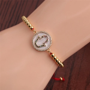 Close-up of golden Hamsa hand bracelet featuring colorful crystals on a wooden background