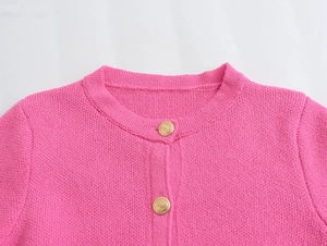 Close-up of rose pink knit cardigan featuring round neck and embossed gold buttons
