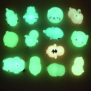 Glow-in-the-dark animal squishy toys in green and yellow light against a dark background