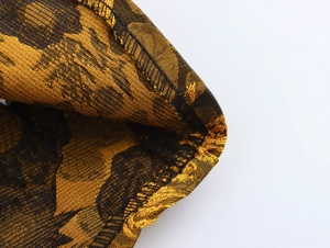 Macro detail of black and gold jacquard fabric texture with precise stitching and hem finish