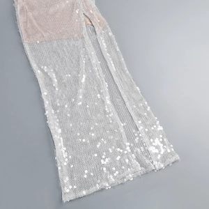 Detail eines silbernen Pailletten-Abendkleides mit Seitenschlitz und glitzerndem Netzstoff