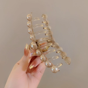 Dettaglio di un grande fermaglio per capelli in acrilico con perle e strass