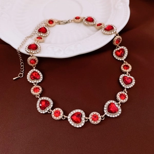 Détail du collier doré avec pierres précieuses rouges en cœur et strass scintillants
