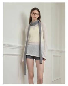 Detail of gray knitted skinny scarf paired with white sheer top and yellow vest