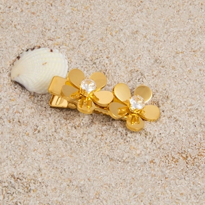 Gold flower hair clip with zircon stones on white sand beach background for summer styling