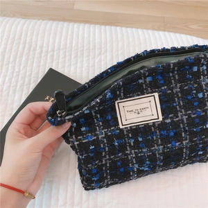Detailed close-up of tweed makeup bag showing blue and black woven texture and zipper