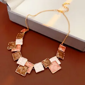 Minimalist gold necklace with square enamel pendants in white, orange and grey tones