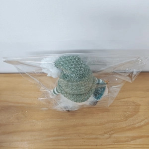 Close-up of a Christmas gnome doll with green striped hat in transparent plastic packaging