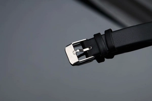 Detailed view of the black leather watch strap with a polished silver metal buckle