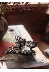 Detailopname van vintage gietijzeren vlinder kandelaar met bronzen afwerking en een waxinelichtje