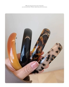 Close-up of four curved spring hair clips in tortoiseshell and solid colors with glossy finish