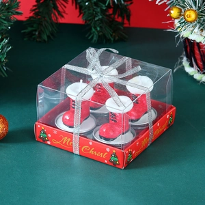 Close-up of four red Christmas boot candles with white fur trim in a clear gift box