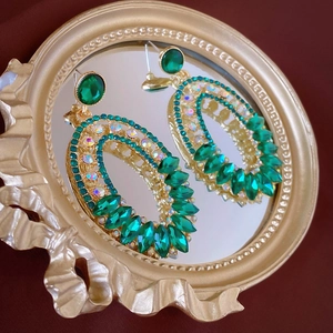 Détail de boucles d'oreilles rétro de luxe avec cristaux vert émeraude sur miroir doré
