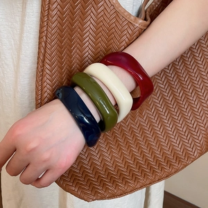 Stack of colorful acrylic geometric bracelets in navy, olive, cream, and burgundy shades