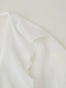Detailed view of white mesh V-neck shirt featuring elegant ruffled edges and textures