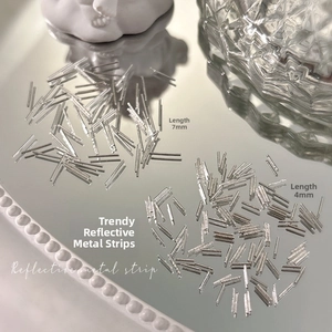Macro shot of 4mm and 7mm silver metallic nail art strips with reflective metal texture