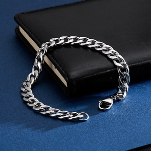 Bracciale a catena cubana NK argento su taccuino in pelle nera con sfondo blu testurizzato