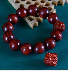 Macro detail of polished redwood beads and exquisitely carved mythical lion charm