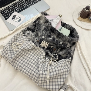 Flat lay of plaid drawstring backpack with laptop and lifestyle items for commute