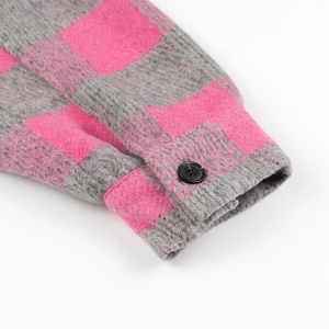 Detailed macro shot of grey and pink plaid shirt cuff with black resin button