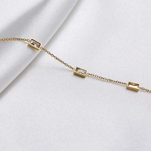 Macro shot of gold pendant necklace with square cubic zirconia on white silk