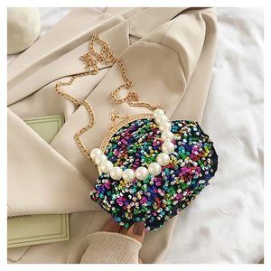 Detail of a vintage sequin shell bag with pearl handle and golden chain on beige blazer