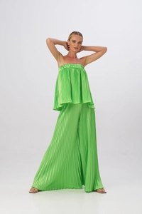 Dettaglio del tessuto plissettato verde brillante su top a fascia e pantaloni larghi
