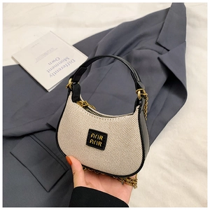 Détail du mini sac demi-lune avec logo AJJR doré et bandoulière en chaîne métallique