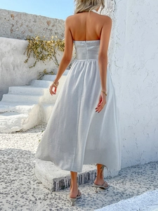 Elegant white backless maxi dress with halter neck shown against Greek architecture scenery