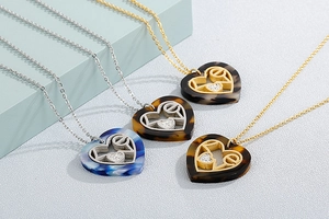 Detail of four gold and silver necklaces featuring heart-shaped LOVE pendants with marble texture