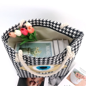 Detail of evil eye tote bag with houndstooth pattern and rope handles with flowers