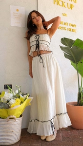 Detail of the white ruffled crop top and maxi skirt set with elegant black drawstring ties