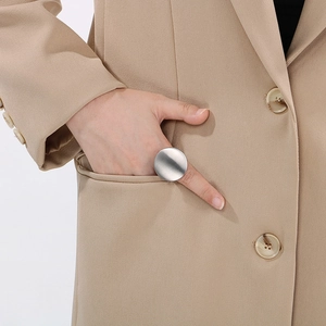 Detail of silver brushed metal round ring worn with a suit for a minimalist professional look