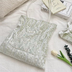 Close-up of light green velvet tote bag with delicate lace embroidery and thin straps