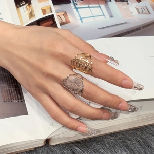 Detail shot of hollow rose rings in gold and silver finish worn by a model