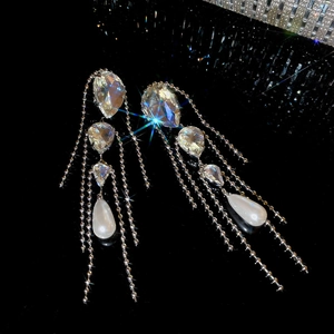 Macro detail of long silver fringe earrings with crystals and teardrop pearls