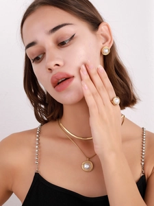 Detail of elegant gold layered necklace with pearl pendant and matching earrings