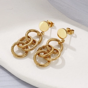 Gros plan de boucles d'oreilles dorées avec trois anneaux entrelacés à texture filetée
