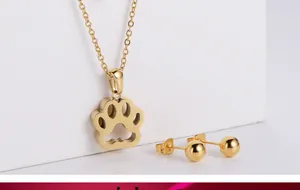 Detail of gold jewelry set showing hollow paw pendant necklace and round stud earrings