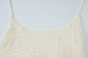 Détail du tissu plissé blanc texturé et des fines bretelles spaghetti de la robe d'été