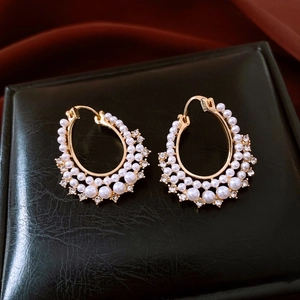 Detailed close-up of French vintage gold pearl earrings with crystals on black leather