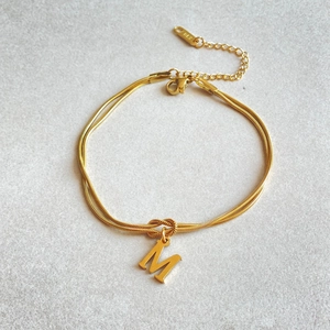 Detail of 18K gold-plated double-layer herringbone chain with letter M pendant