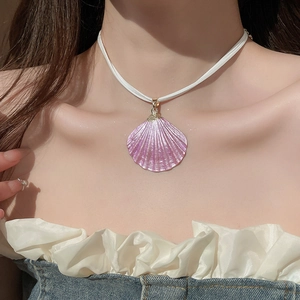 Detail of pink pearlescent shell pendant on a white cord worn by a model
