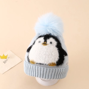 Close-up of light blue knitted hat featuring jacquard penguin pattern and faux fur pompom