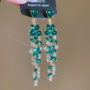 Detail of floral earrings featuring green crystals and elegant long dangling tassels