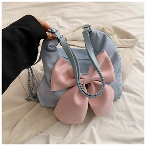 Detail of sky blue handbag featuring a large pink bow and metal chain strap accent