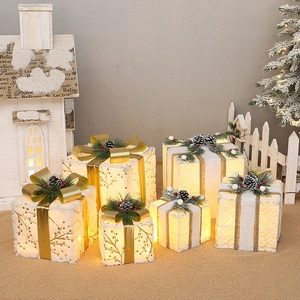 Detail of white flocked Christmas gift boxes with gold ribbons and warm LED lights